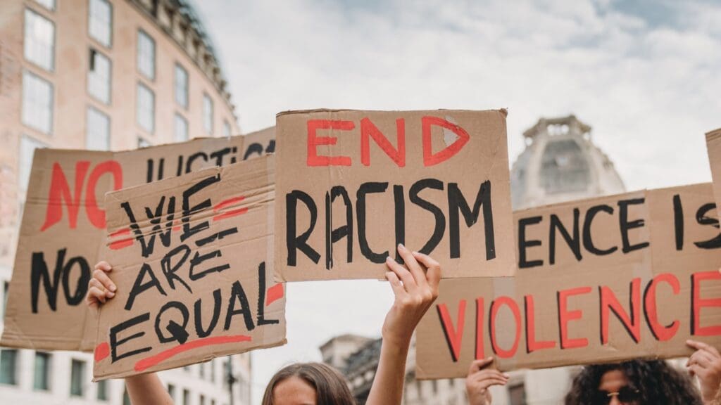 Protesters hold signs demanding an end to racism and violence.