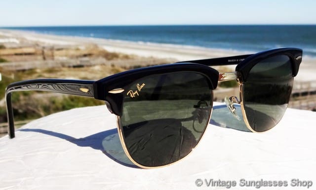 Ray-Ban sunglasses resting on a white surface with a beach and ocean background.