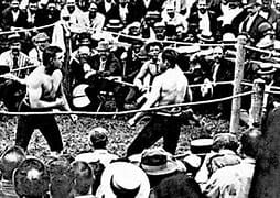 Historic black-and-white photo of a boxing match with a crowded audience.